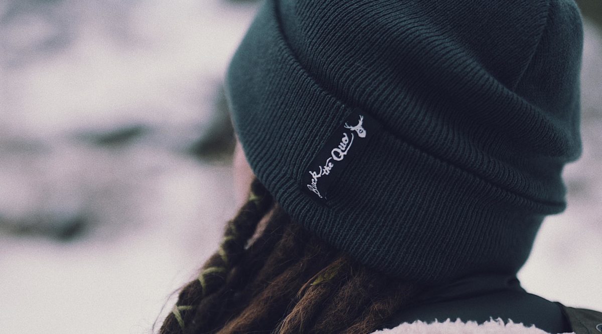 Woman wearing dark gray beanie with Buck the Quo tag