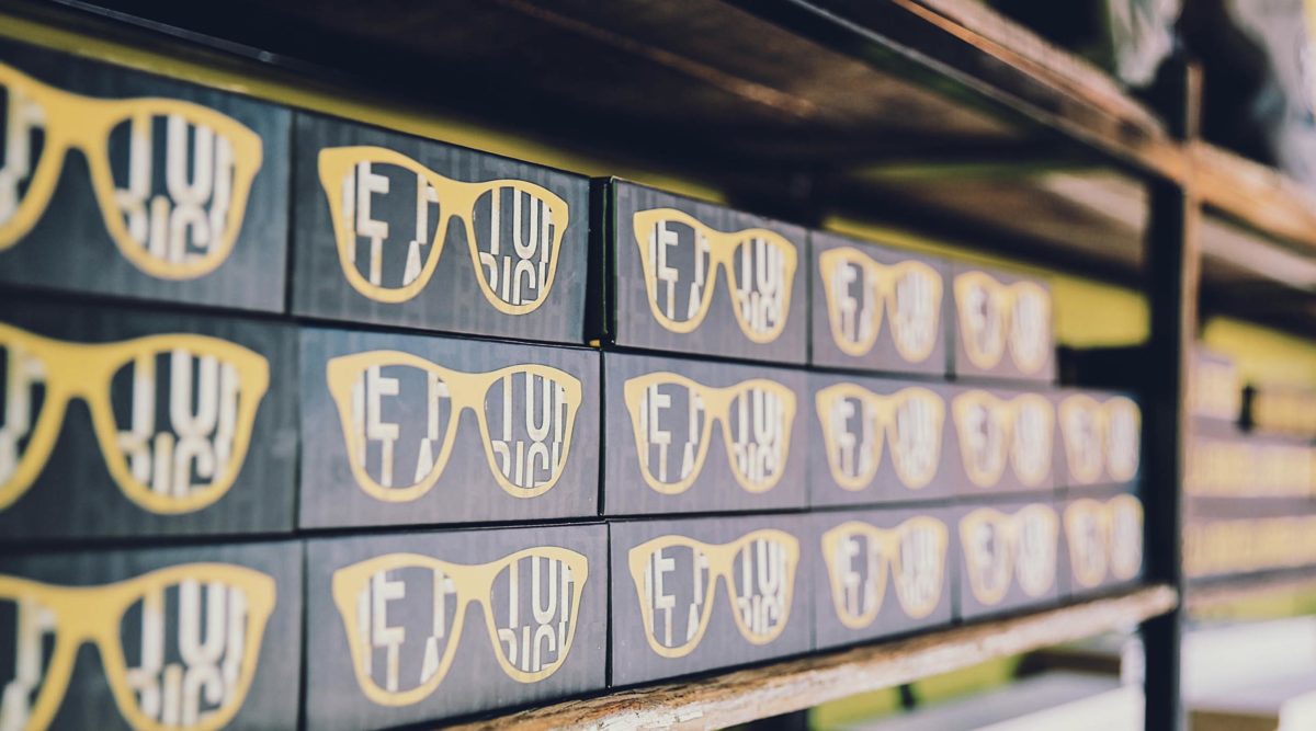 Shelf with rows of black boxes with yellow sunglasses printed on them