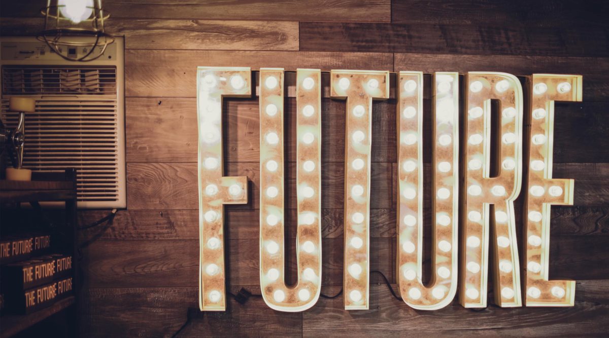 Light up sign that reads FUTURE on wood panel wall