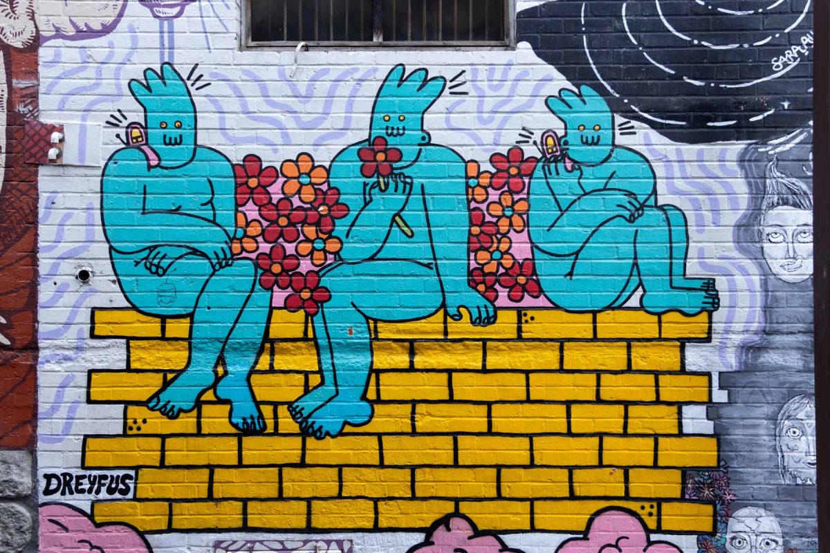 Mural showing three blue humanoids sitting on a golden brick wall with flowers talking on cell phones